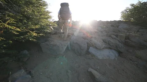 Slow motion scene of young man hiking mountain, sunbeams appearing behind person 스톡 동영상 126726454