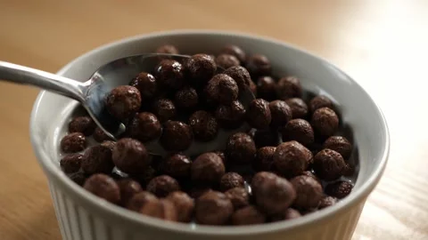 Slow motion scooping choco cereal balls with spoon from bowl full of milk Stock Footage 294697714