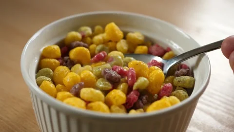 Slow motion scooping colorful fruity cereal with spoon from a bowl full of milk Stock Footage 294697293