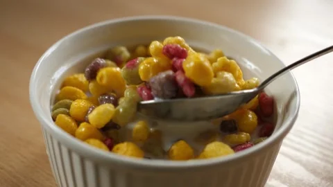 Slow motion scooping colorful fruity cereal with spoon from a bowl full of milk Stock Footage 294697607