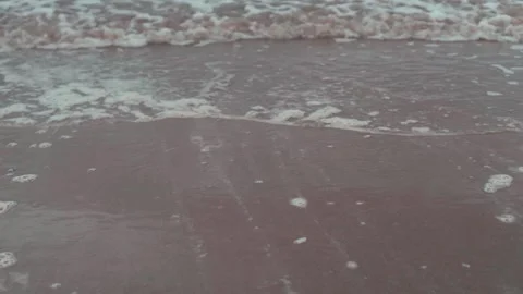 Slow motion sea tide rolling in over sand beach Stock Footage 132540764