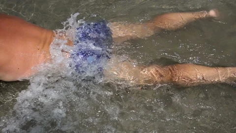 Slow motion of a sea wave rolling on a swimmer lying on the shore. Stock Footage 114293980