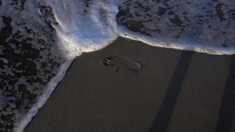 Slow motion of sea wave washes the tracks in the sand. Stock Footage 113192910