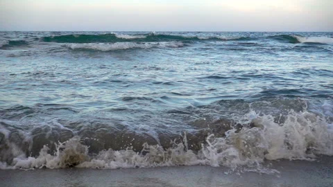 Slow motion of the sea waves passes through a small stone reef and sandy beach. Stock Footage 95761007