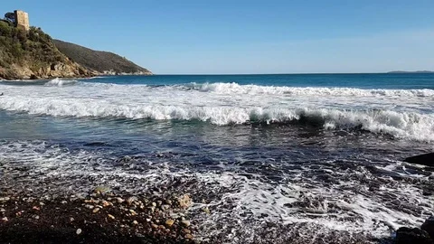 Slow Motion Sea waves on a rocky lone beach in a sunny day Stock Footage 107880713