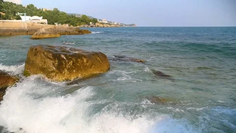 Slow motion sea waves splashing against rocks on blue sky Stock Footage 80656006