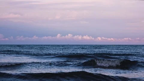 Slow motion sea waves at sunset with purple clouds on horizon, peaceful ocea Stock Footage 346395064