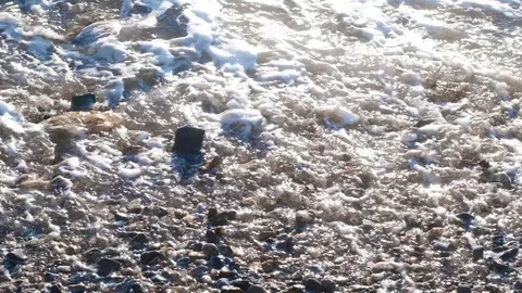 Slow motion sea waves with white foam washing up pebble stones on the beach Stock Footage 121532941