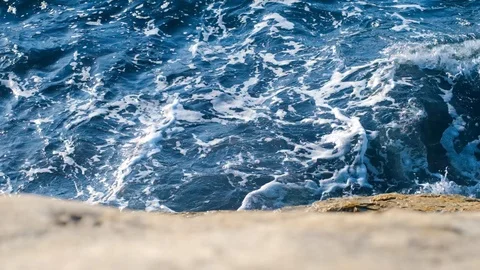 Slow motion sea waves with white foam breaking at the rocks on the beach Stock Footage 121534618