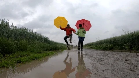 Slow motion of senior couple jumping in rain puddle Stock Footage 90337607
