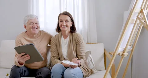 Slow motion senior couple sit closely while husband holds tablet 库存影片 339561855