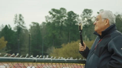Slow motion of senior man holding selfie stick with phone at a park Stock Footage 117077984