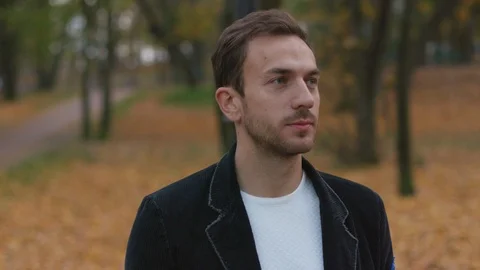 Slow motion serious handsome portrait young man look at camera in park Stock Footage 102744286