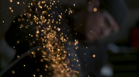 Slow motion shallow focus golden sparks shooting upward man in soft focus in BG Stock Footage 64086961