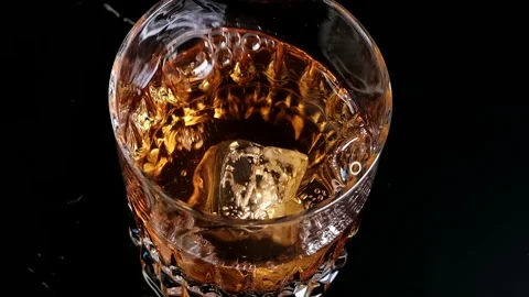 Slow Motion Shoot On Ice Cube Dropping Into The Whiskey Stock Footage 220773529