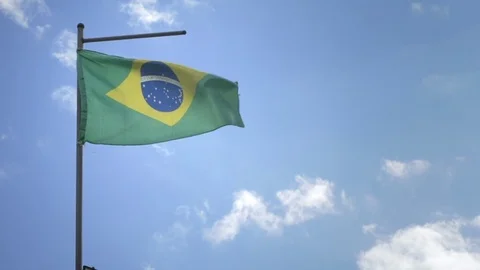 Slow motion shooting of the Brazilian flag against the blue sky Stock Footage