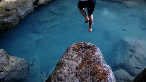 Slow motion shot of active young man jumping from the cliff into water Stock Footage 112624469