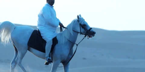 Slow motion shot of an Arabic man riding a horse in a desert. Stock Footage 46871532