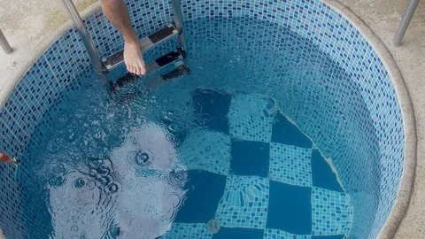 Slow motion shot of an athletic man jumping and dipping into a cold pool Video stock 119801494