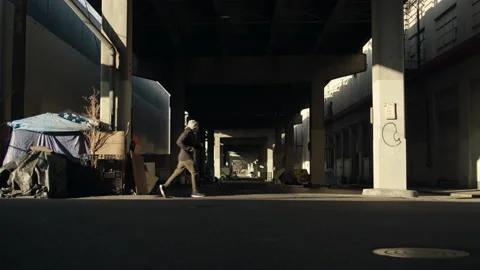 Slow motion shot of athletic man jogging in front of city overpass 動画素材 153344986