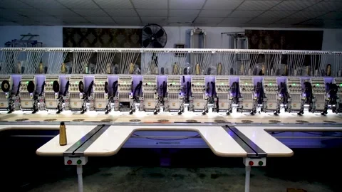 Slow motion shot of automatic embroidery machine with multiple heads in text Stock Footage 199272368