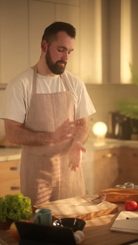 A slow-motion shot of a bearded man in an apron clapping his hands to remove Stock Footage 304373248