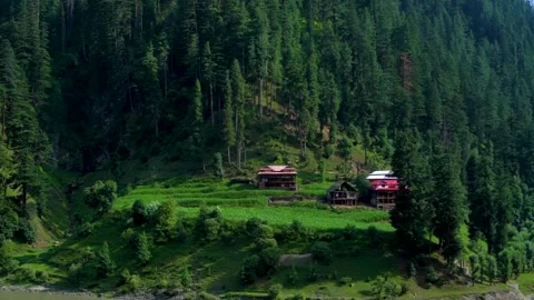 Slow motion shot of beautiful huts with lush green mountains and river in hi Stock Footage 200744502