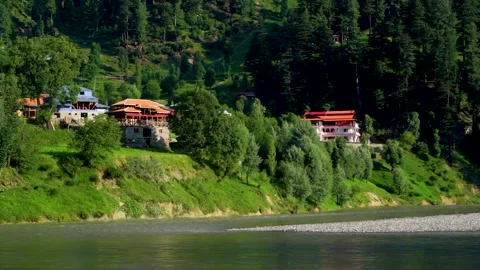 Slow motion shot of beautiful huts with lush green mountains and river in hi Stock Footage 200744506