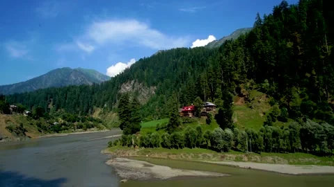 Slow motion shot of beautiful huts with lush green mountains and river in hi Stock Footage 200744704