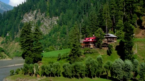 Slow motion shot of beautiful huts with lush green mountains and river in hi Stock Footage 200744864