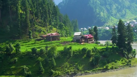 Slow motion shot of beautiful huts with lush green mountains and river in hi Stock Footage 200744871