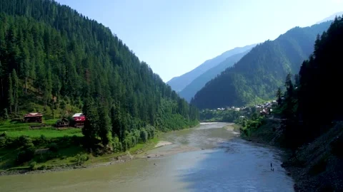 Slow motion shot of beautiful huts with lush green mountains and river in hi Stock Footage 200759003