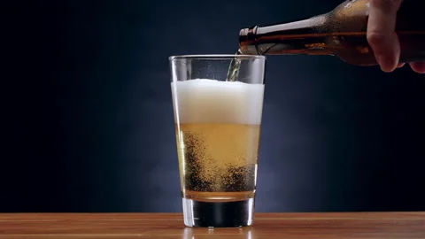 Slow motion shot of beer being poured into pint glass on bar Stock Footage 134521317