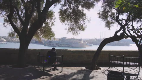 Slow Motion Shot From Behind Man Sitting On Bench In Beautiful Oceanside Park Stock Footage 264769446