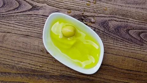 Slow Motion Shot of Black Olive Falling into Fresh Olive Oil 動画素材 138752795