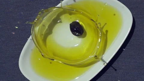 Slow Motion Shot of Black Olive Falling into Fresh Olive Oil 動画素材 138797810