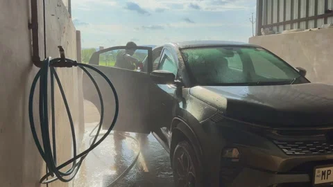 Slow motion shot of black SUV undergoing a car wash inside a covered washing Vídeos de archivo 314360878