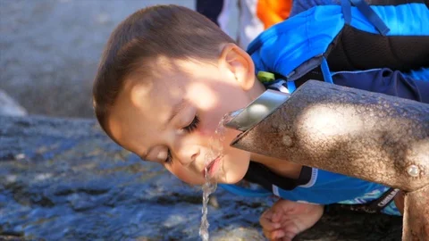 Slow motion shot of boys drinking from an outdoor water fountain Stock Footage