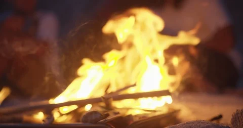 Slow motion shot of burning flames during night with blurred people behind it Stock Footage 125815262