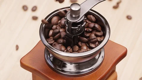 Slow motion shot of coffee beans falling into vintage grinder Stockbeeldmateriaal 94660694