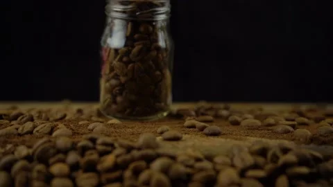 Slow motion shot of coffee beans falling from the glass jar on the wooden table	 Stock Footage 134835032