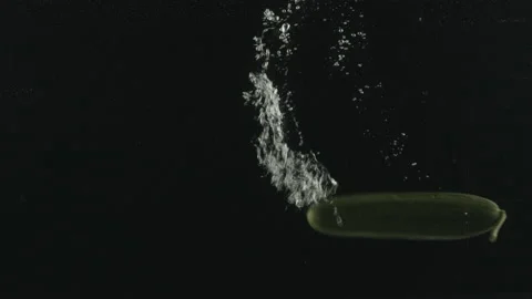 Slow Motion Shot of Cucumbers Falling into Water on black Background at. Stock Footage 171544640