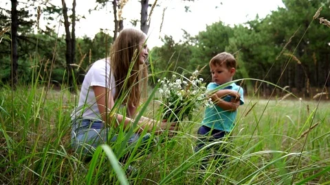 Slow motion shot on defocused young woman smiling at little boy smelling Stock Footage 104146747