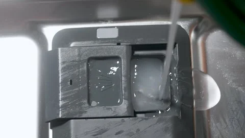 Slow-motion shot of dishwasher detergent being poured into a dirty dishwaser Stockbeeldmateriaal 313908096