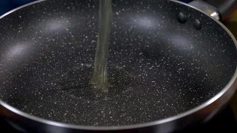 Slow motion shot of an egg falling on a hot nonstick fry pan Stock Footage 112912407
