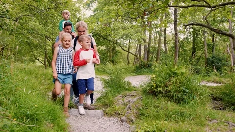 Slow Motion Shot Of Family Hiking Along Path By River In UK Lake District Stock Footage