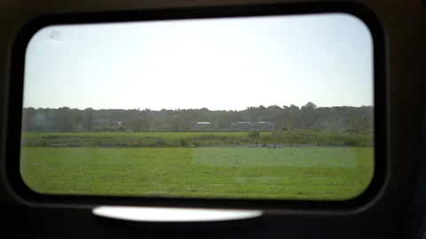Slow-motion shot of a field through a traveling train's window Stock Footage 210474411