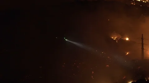 Slow motion shot of a firefighting helicopter, extinguishing wildfires, at Stock Footage 121810041