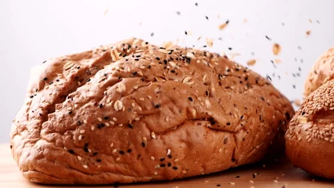 Slow-motion shot fresh bread with sesame seeds falling on a table Stock Footage 165347223