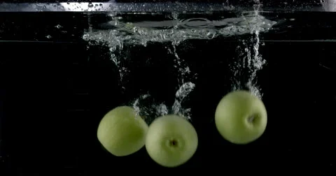 Slow-motion shot of a fresh green apple being thrown into water. Stock Footage 300483454